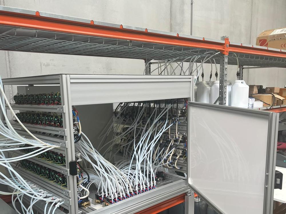 Rack SMD 96 con decenas de bombas peristálticas y tubos hacia un cabezal dosificador